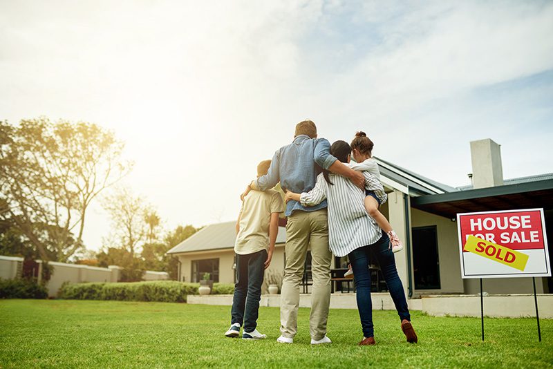 Family in front of a house with a sold sign