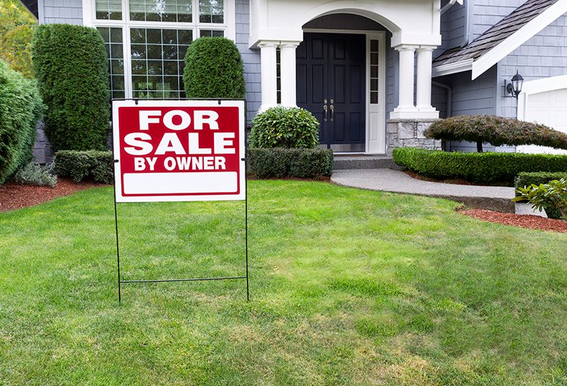 Home with blue siding exterior with a for sale sign in the front yard